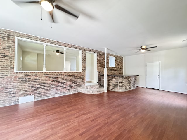 710 Gadsden Loop, Walterboro, SC 29488 - unfurnished living room featuring a ceiling fan, brick wall, and wood finished floors