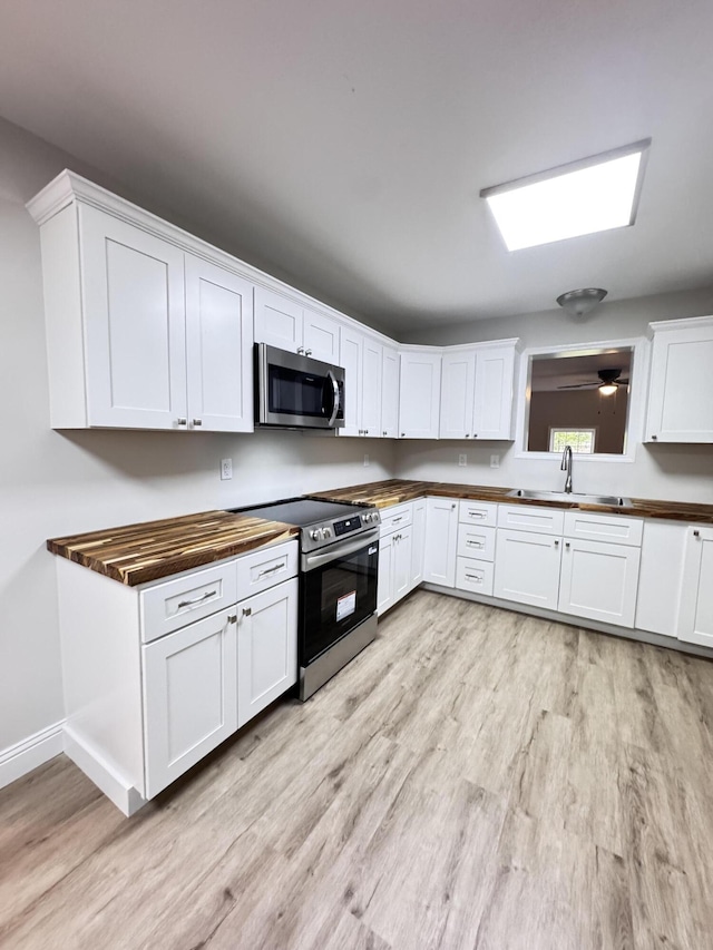710 Gadsden Loop, Walterboro, SC 29488 - kitchen featuring stainless steel appliances, a sink, light wood-style floors, wooden counters, and white cabinetry