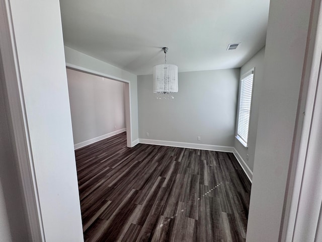 unfurnished dining area with a chandelier and dark wood-type flooring