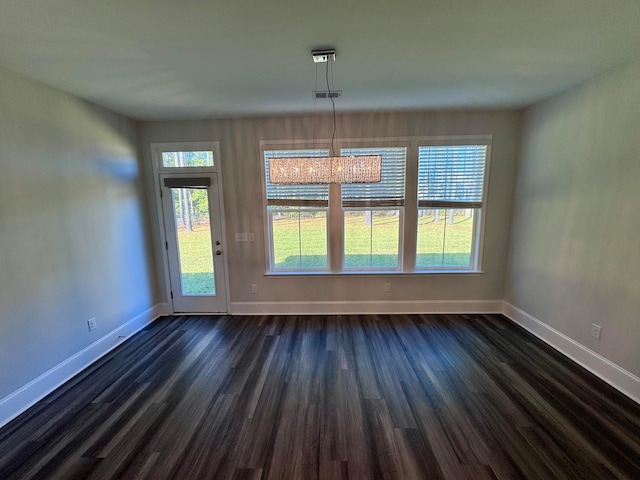 unfurnished dining area featuring a healthy amount of sunlight, dark hardwood / wood-style floors, and a notable chandelier