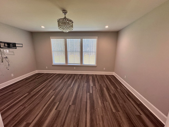 empty room featuring a chandelier and dark wood-type flooring