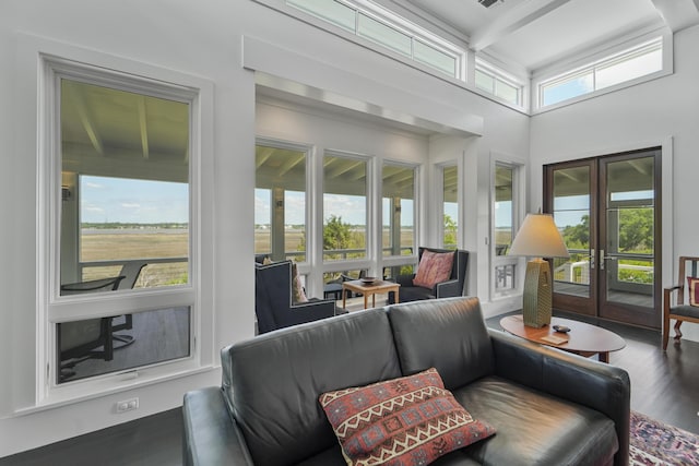 sunroom / solarium featuring beam ceiling, french doors, a high ceiling, and wood finished floors