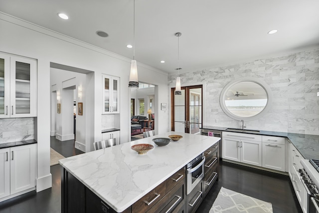 kitchen with a sink, white cabinets, backsplash, and double oven range