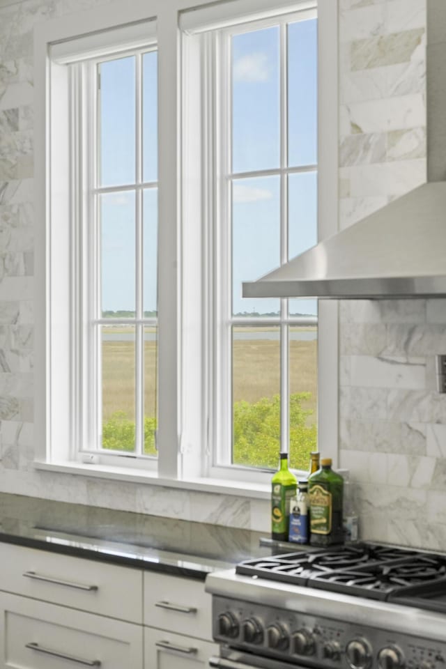 kitchen featuring plenty of natural light, stainless steel gas range, backsplash, and wall chimney range hood