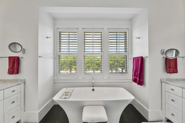 bathroom featuring baseboards, a freestanding bath, and vanity
