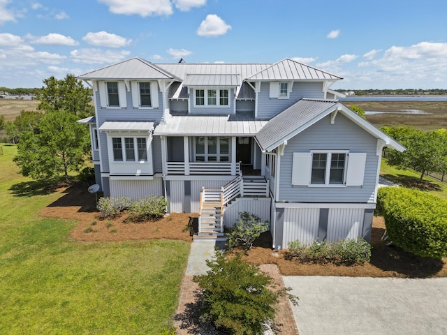 view of front of home with a standing seam roof, metal roof, a front yard, stairway, and a water view