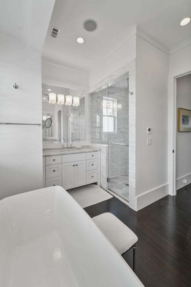 full bath with visible vents, a freestanding bath, a shower stall, wood finished floors, and ornamental molding