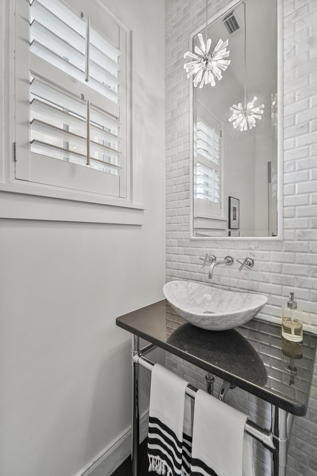 bathroom with a chandelier, decorative backsplash, a sink, and plenty of natural light