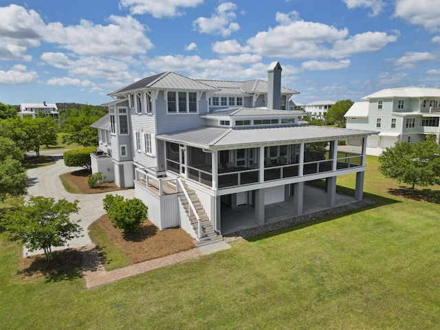 rear view of house with a lawn, metal roof, a sunroom, and a chimney