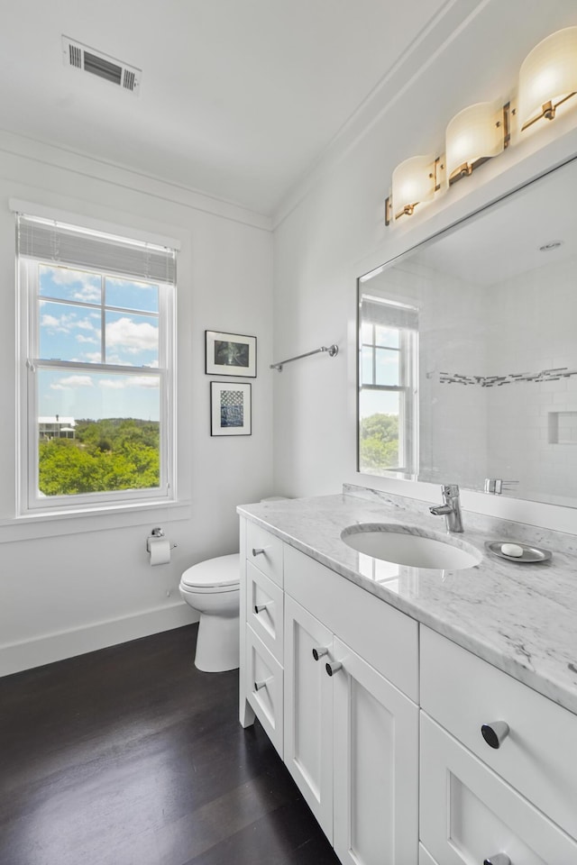 bathroom featuring vanity, toilet, baseboards, wood finished floors, and visible vents