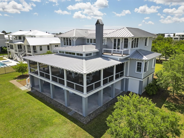 back of house with a patio area, a balcony, a standing seam roof, a yard, and metal roof