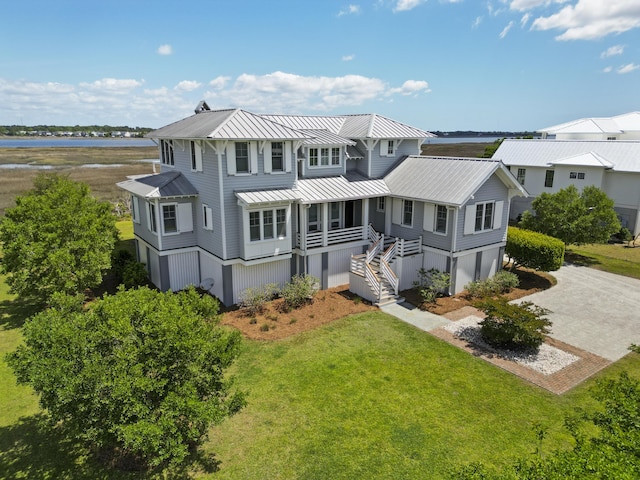 exterior space with a standing seam roof, metal roof, driveway, stairway, and a yard