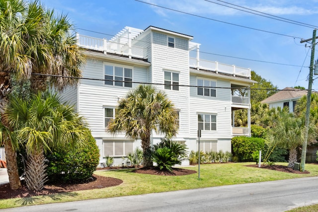 view of front of house with a balcony and a front lawn