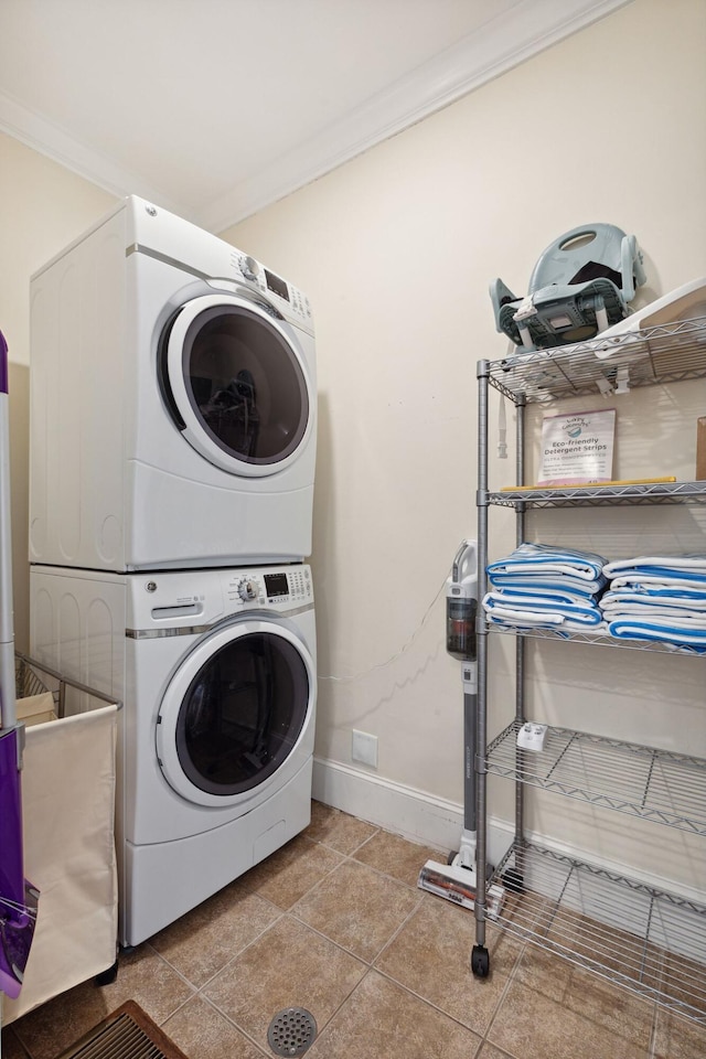 washroom featuring crown molding, light tile floors, and stacked washer and dryer