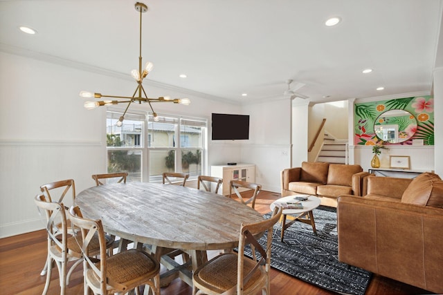 dining area featuring ornamental molding, dark wood-type flooring, and ceiling fan with notable chandelier