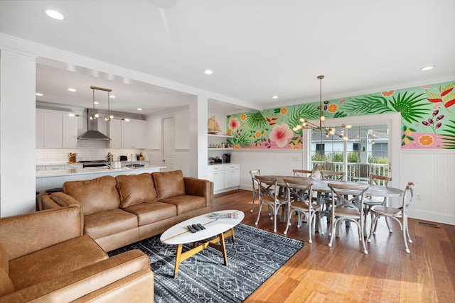 living room with crown molding, hardwood / wood-style flooring, and an inviting chandelier