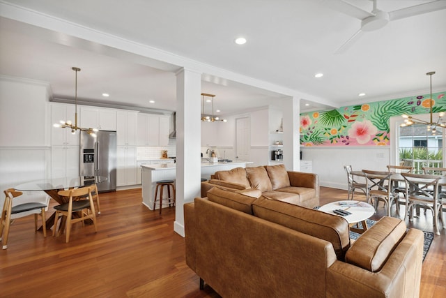 living room with an inviting chandelier, ornamental molding, and light wood-type flooring