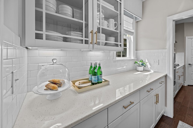 255 Saxony Loop, Summerville, SC 29486 - kitchen with light stone counters, white cabinets, dark wood-type flooring, tasteful backsplash, and glass insert cabinets