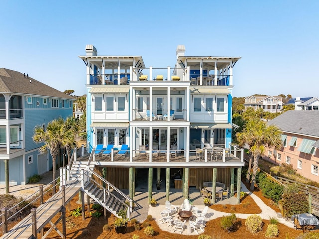 rear view of property featuring a patio area, a fire pit, and a balcony