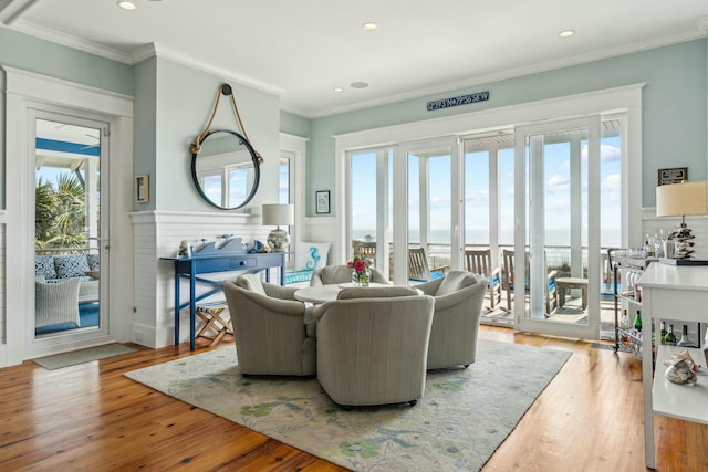 living room with a wainscoted wall, ornamental molding, light wood-style flooring, and recessed lighting