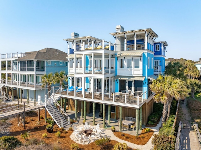 back of property featuring an outdoor fire pit, a balcony, a chimney, stairs, and a patio area