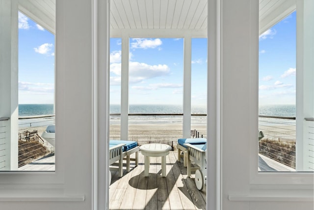 doorway to outside featuring a water view, a beach view, and a wealth of natural light