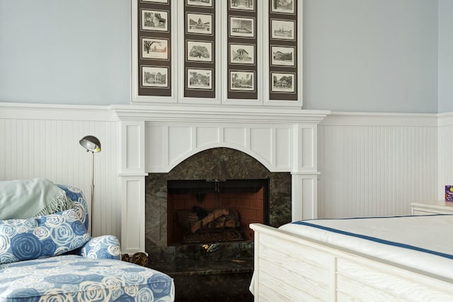 bedroom with wainscoting and a premium fireplace