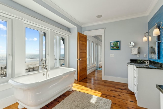 full bath with a freestanding tub, ornamental molding, wood finished floors, and vanity