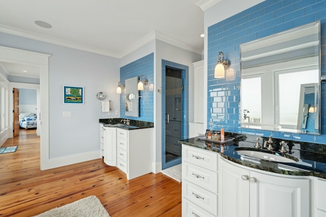 bathroom featuring a stall shower, ornamental molding, a sink, and wood finished floors