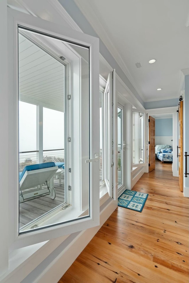 doorway with light wood finished floors, a barn door, ornamental molding, and recessed lighting