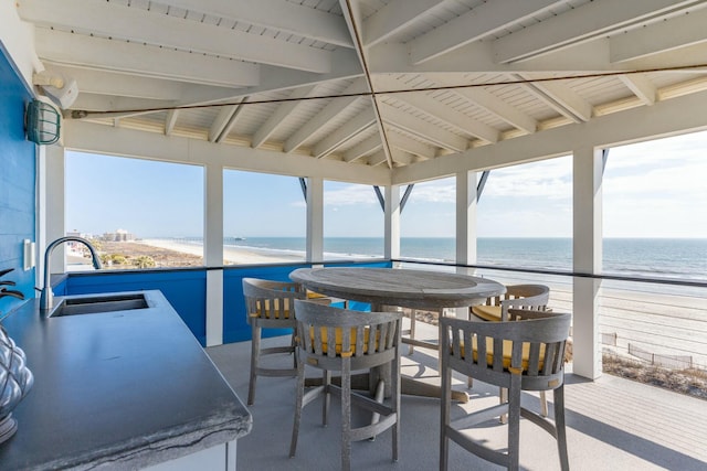 sunroom / solarium featuring a water view, a healthy amount of sunlight, and a sink