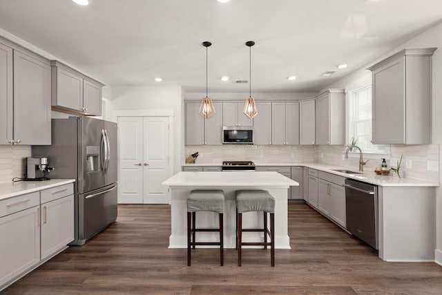 kitchen featuring gray cabinetry, a kitchen island, dark hardwood / wood-style flooring, and stainless steel appliances