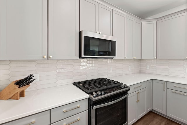 kitchen with gray cabinets, gas stove, and backsplash