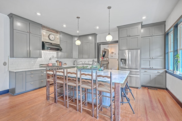 kitchen featuring light hardwood / wood-style floors, hanging light fixtures, gray cabinetry, and stainless steel fridge with ice dispenser