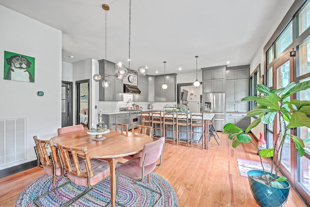 dining room with light hardwood / wood-style flooring and an inviting chandelier