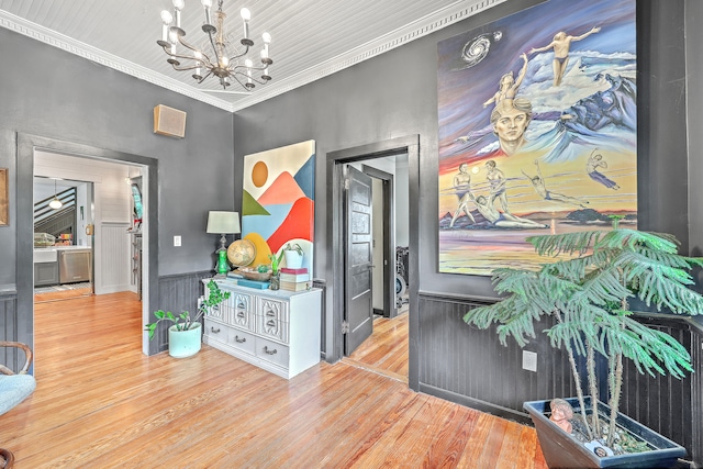 hallway featuring light hardwood / wood-style flooring, ornamental molding, and an inviting chandelier