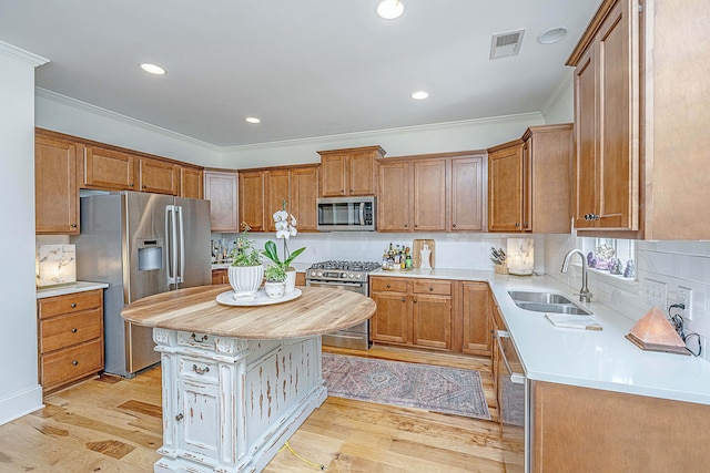 kitchen with visible vents, a sink, light wood-style floors, appliances with stainless steel finishes, and crown molding