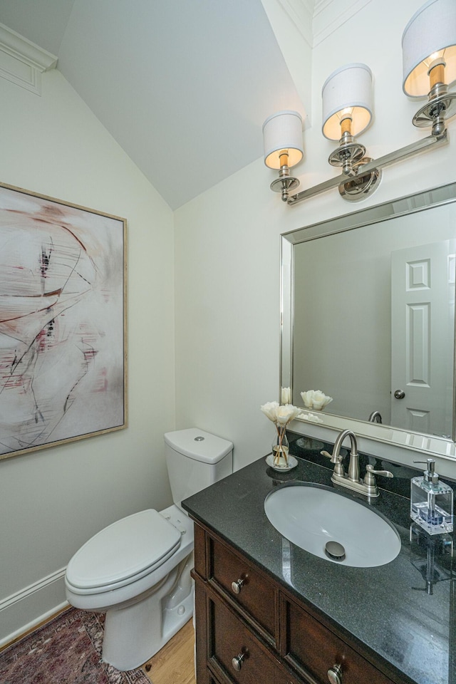 half bathroom with wood finished floors, toilet, vanity, and vaulted ceiling