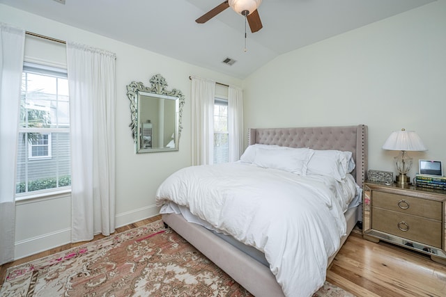 bedroom with a ceiling fan, visible vents, baseboards, lofted ceiling, and light wood-style floors