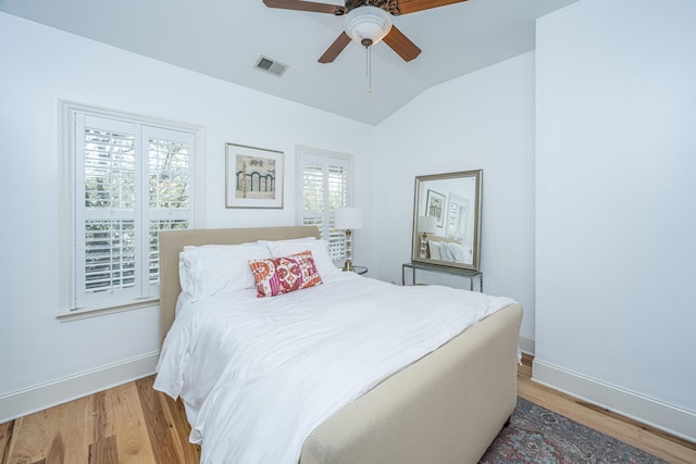 bedroom with visible vents, ceiling fan, baseboards, vaulted ceiling, and light wood-style flooring