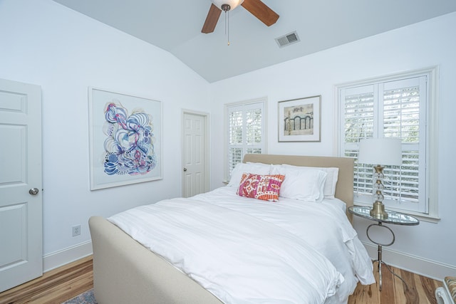 bedroom with visible vents, multiple windows, wood finished floors, and vaulted ceiling