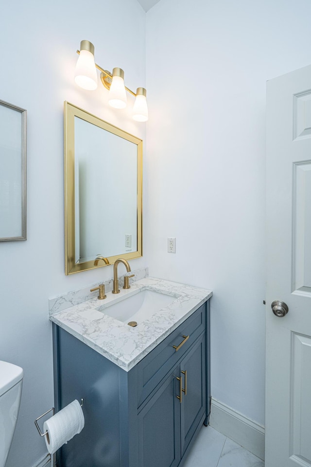 half bath featuring vanity, toilet, baseboards, and marble finish floor