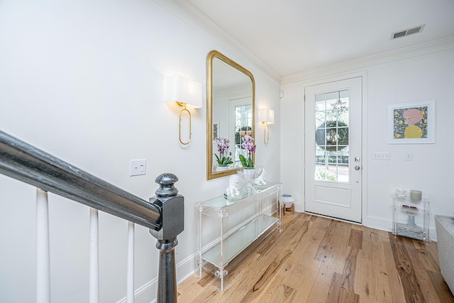 foyer with visible vents, wood finished floors, baseboards, and ornamental molding