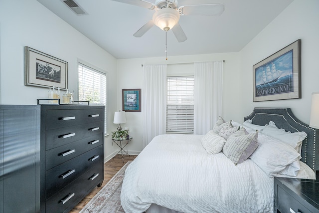 bedroom featuring ceiling fan, wood finished floors, visible vents, and baseboards