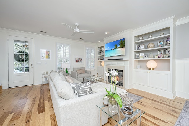 living room featuring visible vents, light wood-style flooring, and ornamental molding