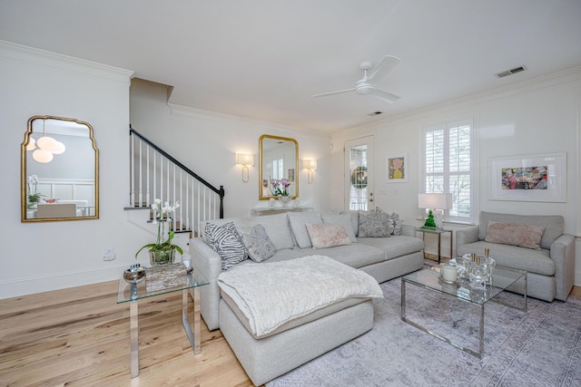 living area featuring visible vents, stairs, ornamental molding, wood finished floors, and a ceiling fan