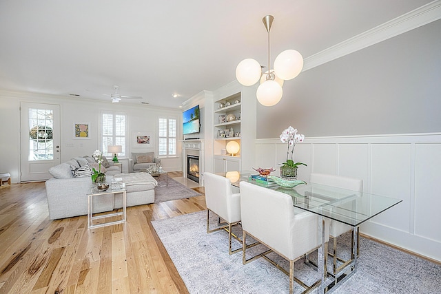 dining room with built in features, a fireplace with flush hearth, plenty of natural light, and ornamental molding