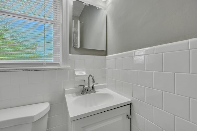 bathroom with vanity, toilet, and tile walls