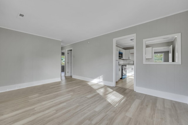 spare room with light wood-type flooring, ornamental molding, and wooden walls