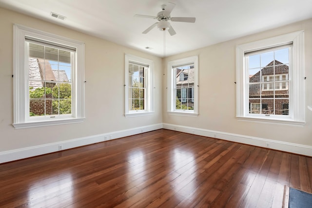 spare room with plenty of natural light, dark wood-style flooring, and baseboards